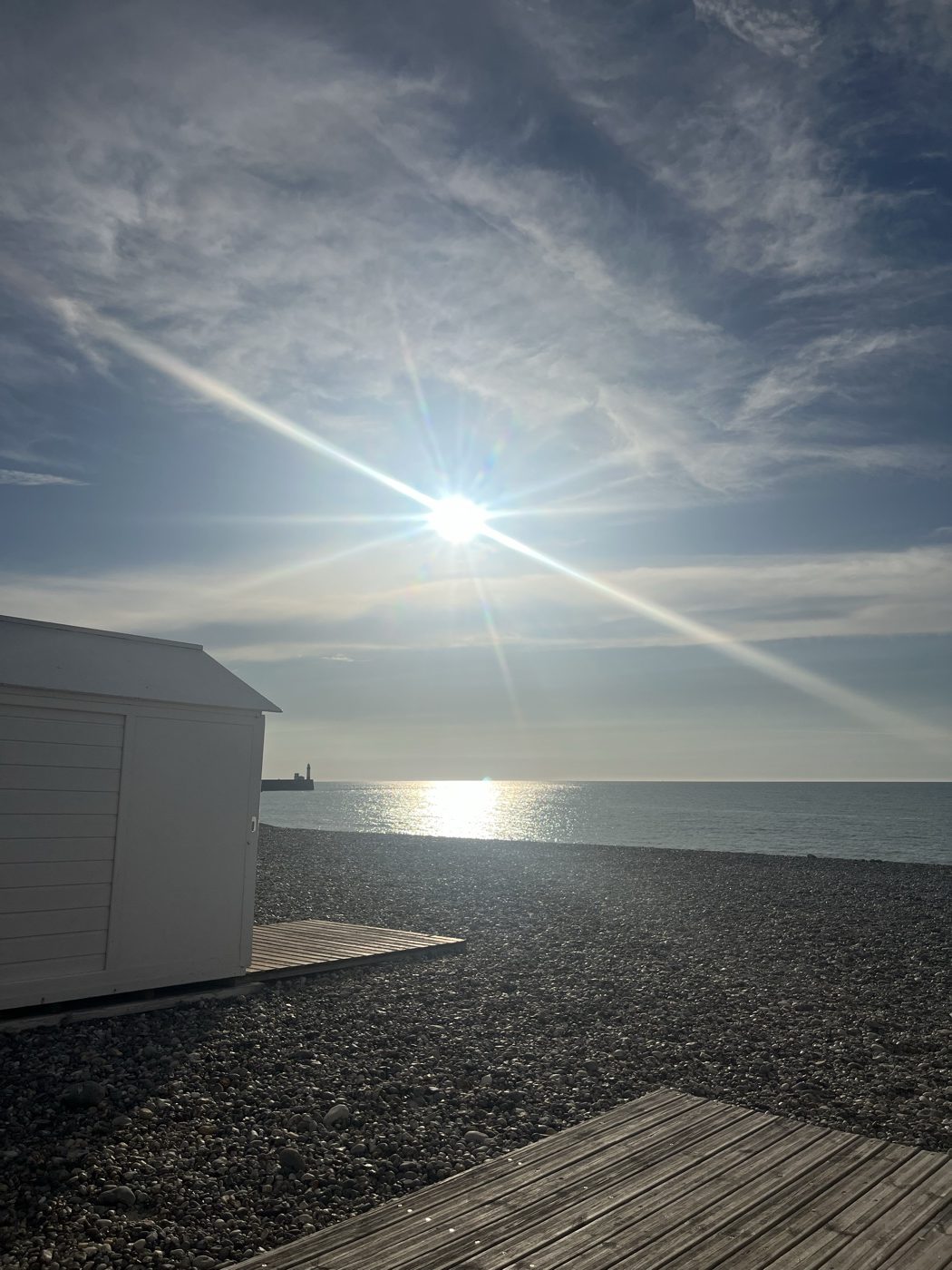 Cabine de plage blanche sur les galets, soleil sur la mer